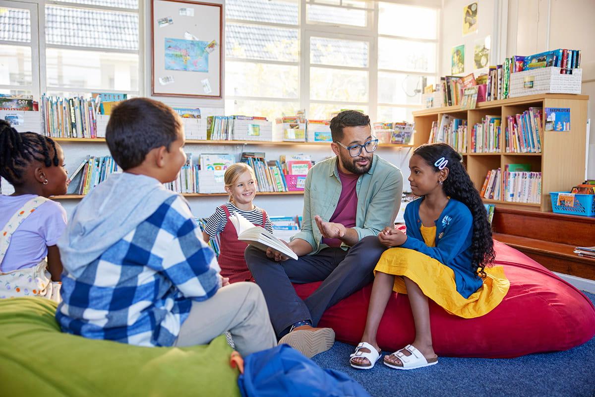 A male teacher in a classroom setting with four students in San Juan College's Teacher Residency Program.